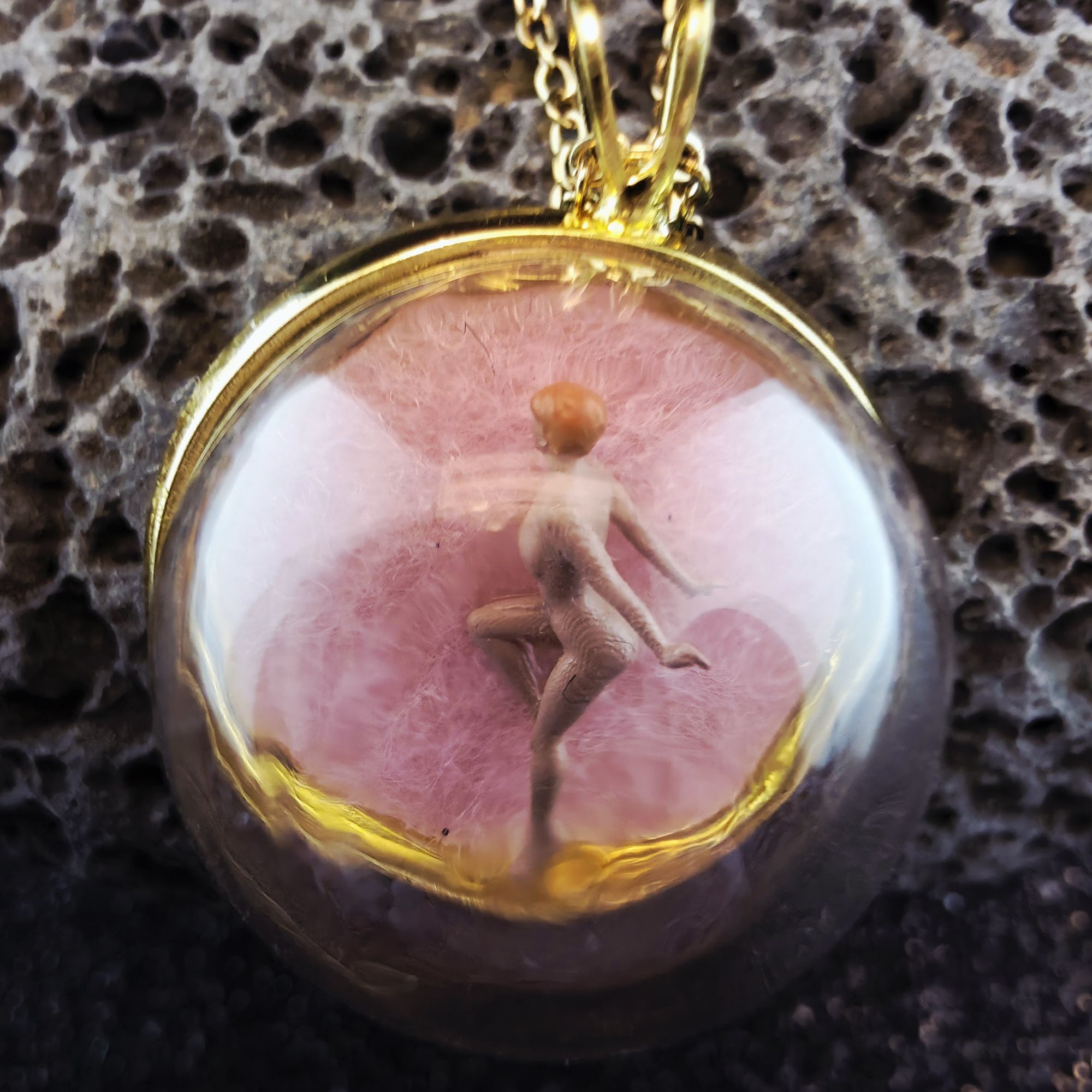 médaillon en métal doré contenant une femme nue rose sous bulle de verre - petite planete