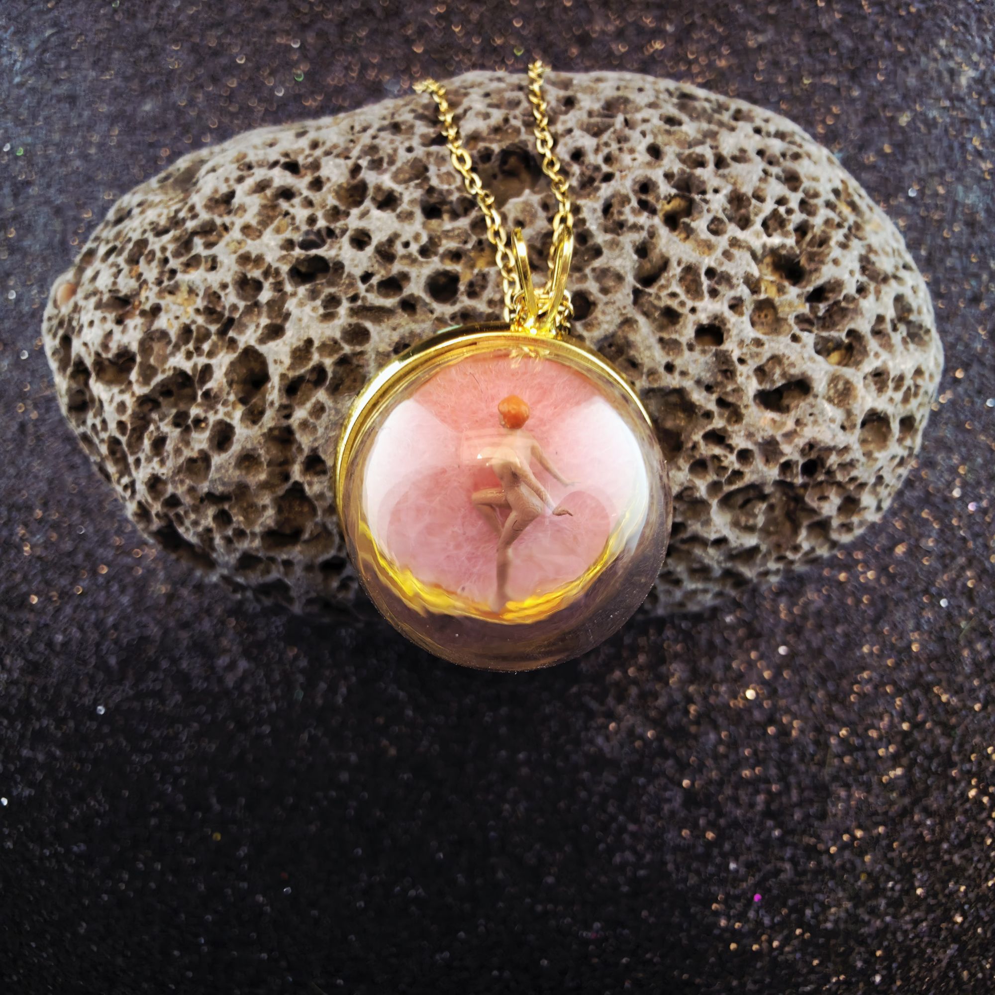 médaillon en métal doré contenant une femme nue rose sous bulle de verre - petite planete