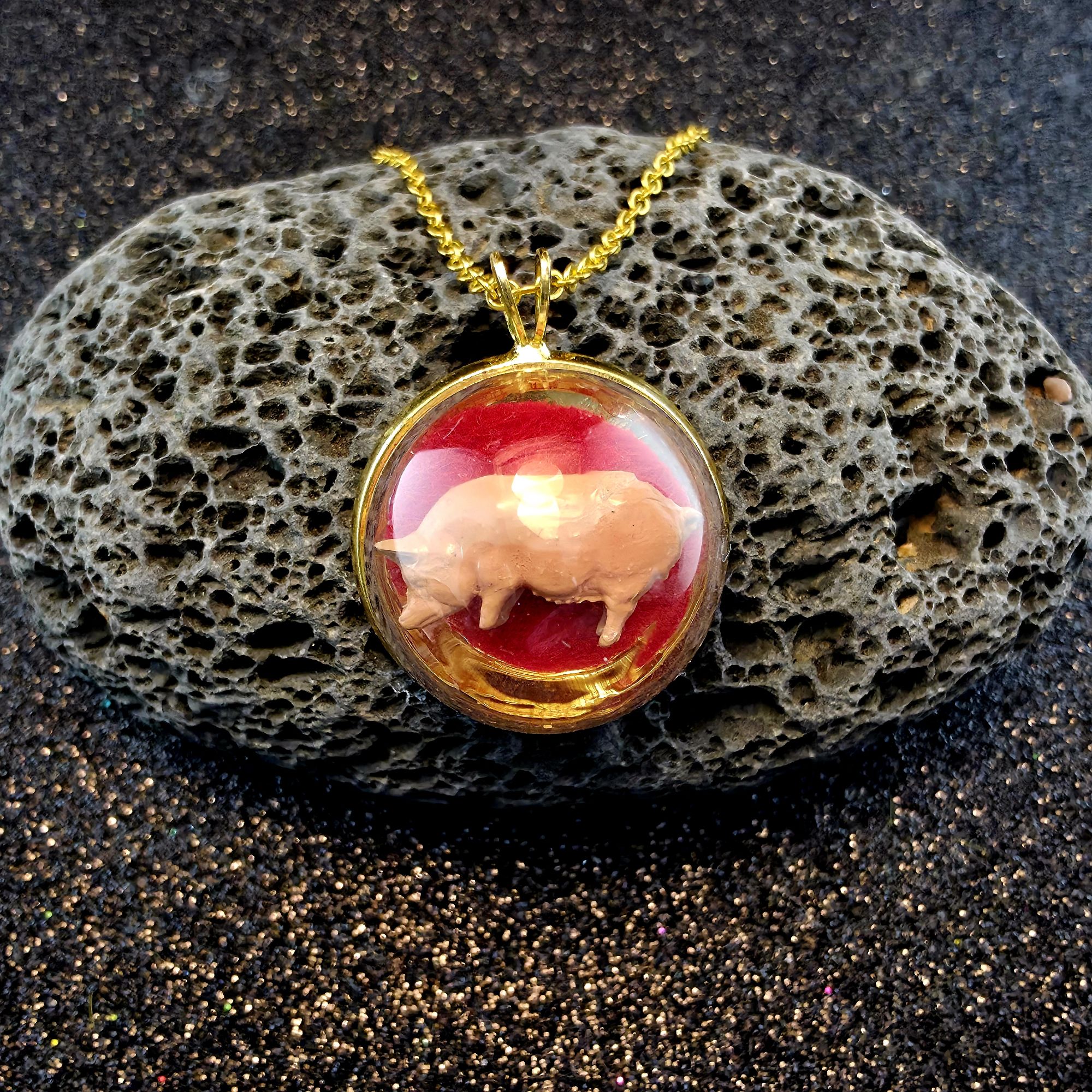 médaillon en métal doré contenant un grand cochon fond fuschia sous bulle de verre - petite planete