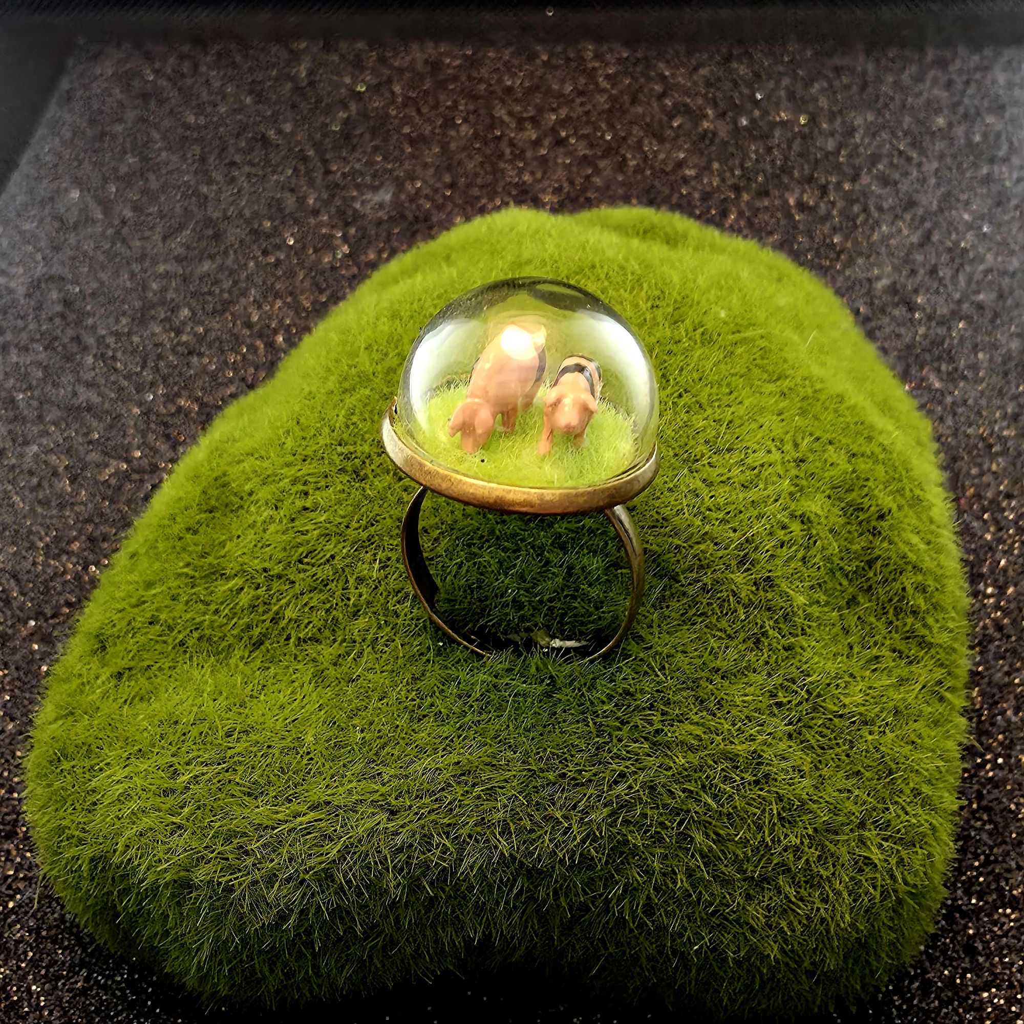 Bague en métal et bulle de verre présentant deux mini cochons