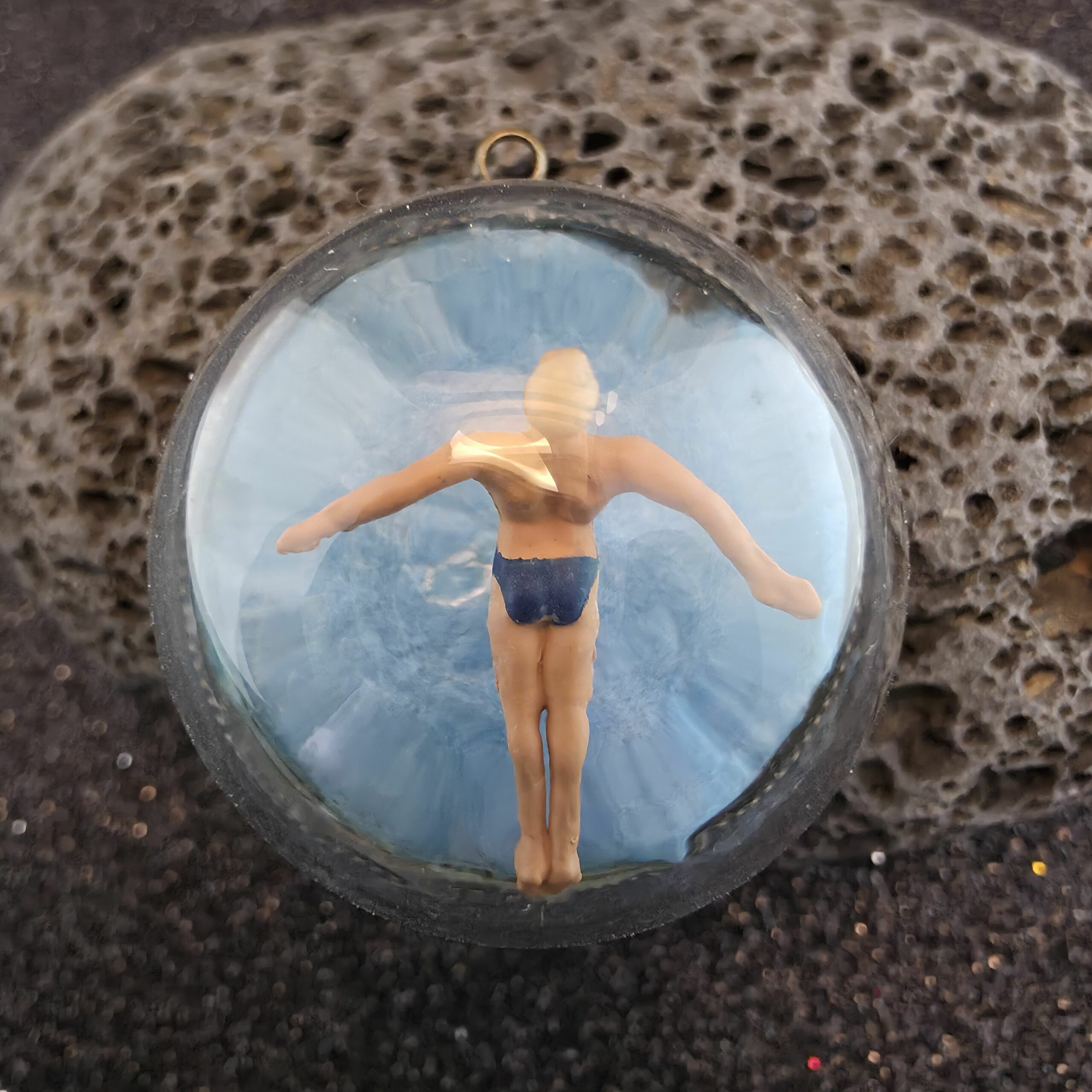 médaillon en métal bronze contenant un plongeur en saut de l'ange sur fond bleue sous une bulle de verre - petite planete