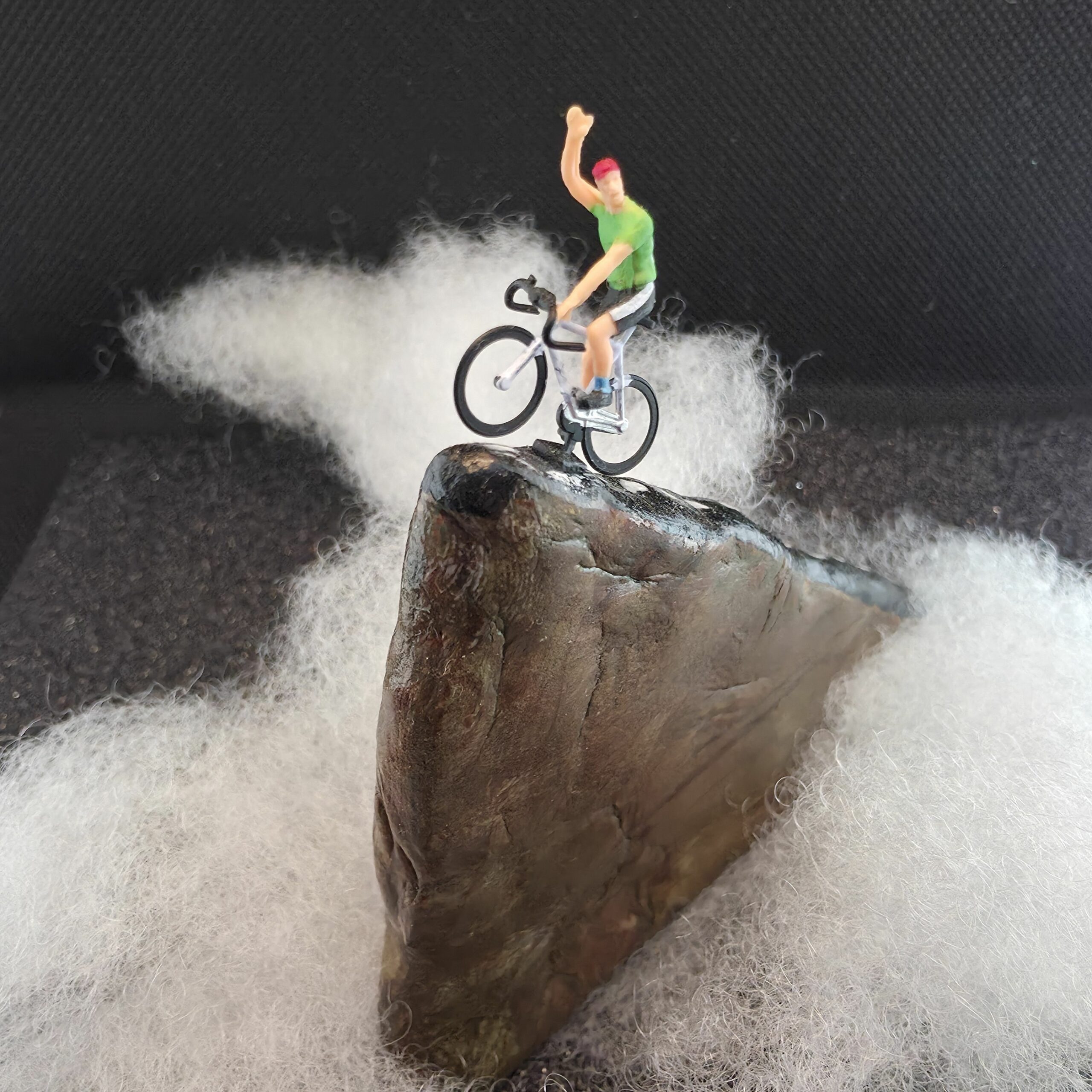 Installation en argile peinte à la main en forme de route escarpée au bout de laquelle un cycliste gagne sa course - petite planete