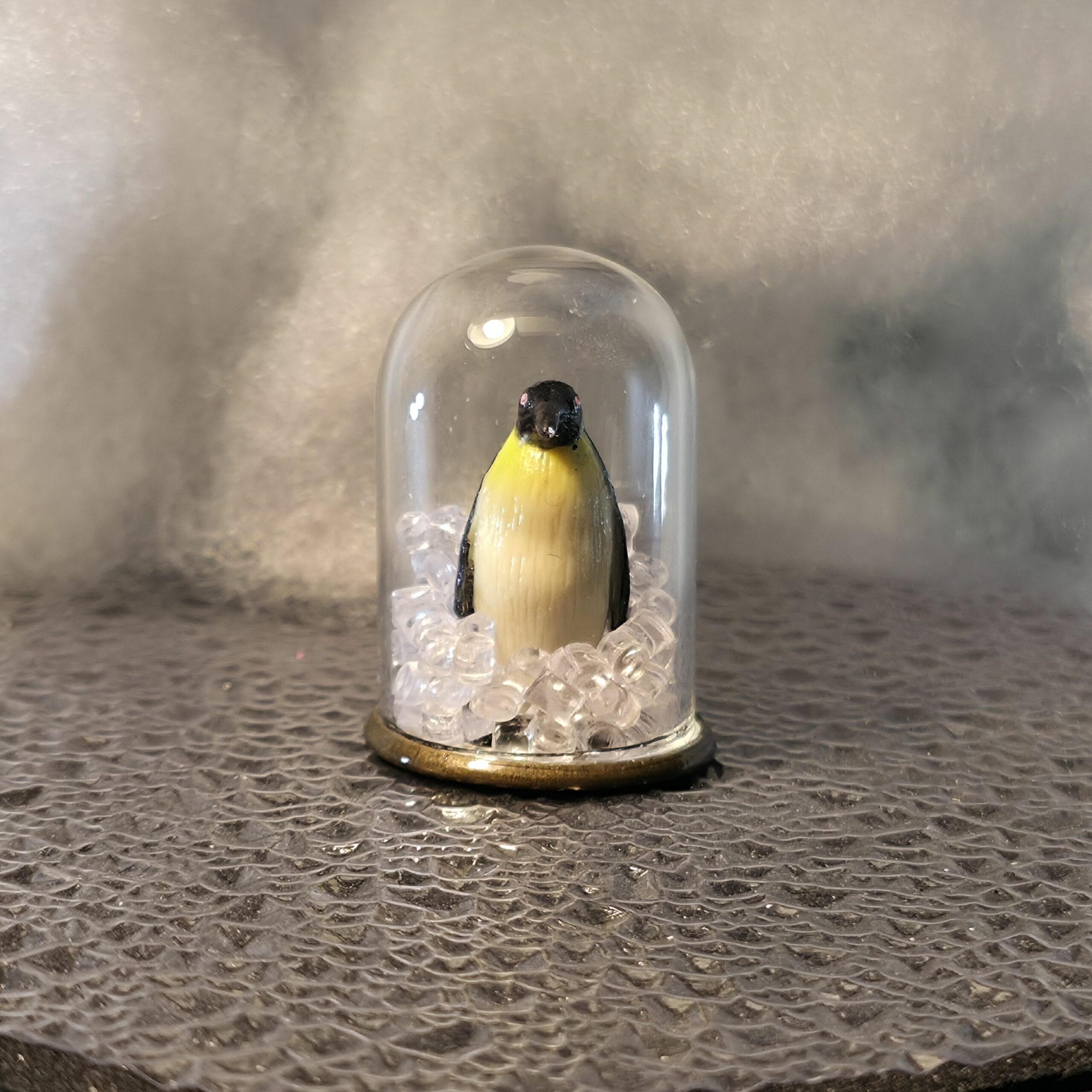 bulle de verre contenant une figurine de pingouin/manchot empereur debout, entouré de glaçons pour l'éternité - petite planete