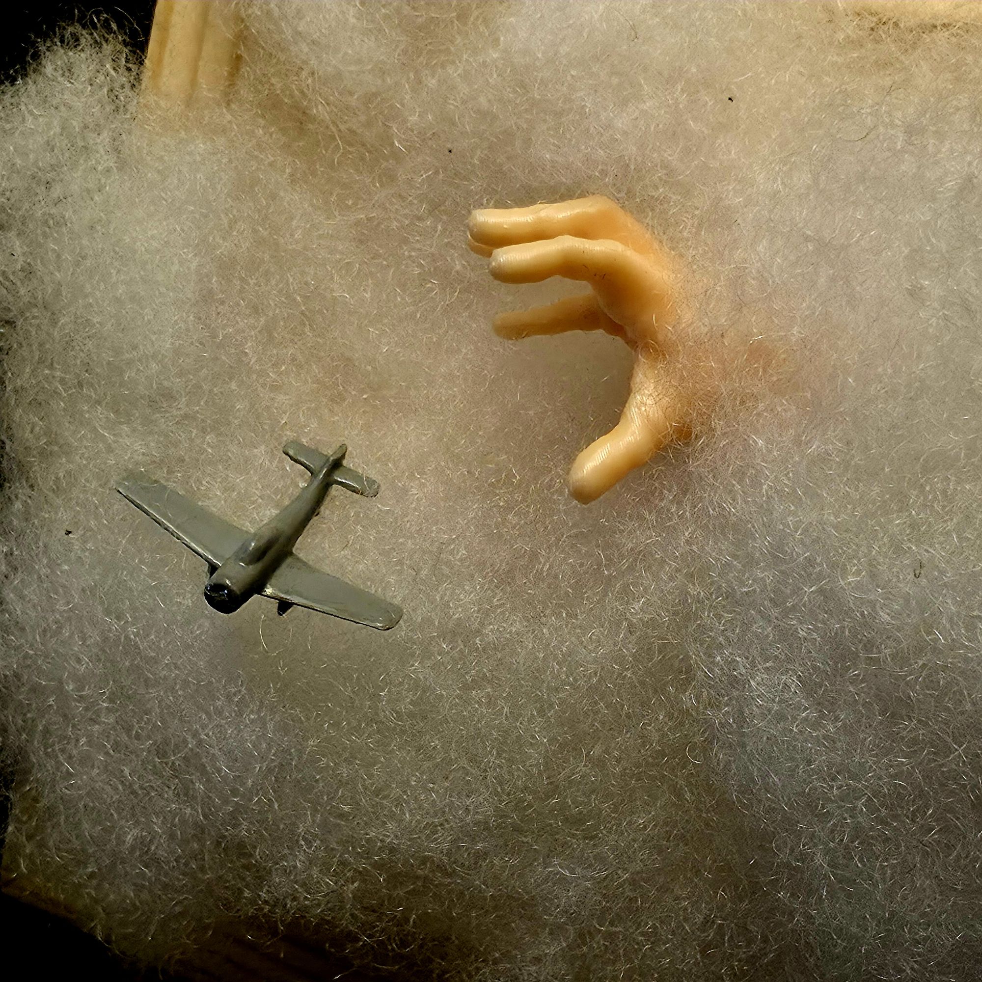 Petit tableau figurant un avion en perdition dans un nuage qu'essaie d'attraper une main géante qui surgit du nuage