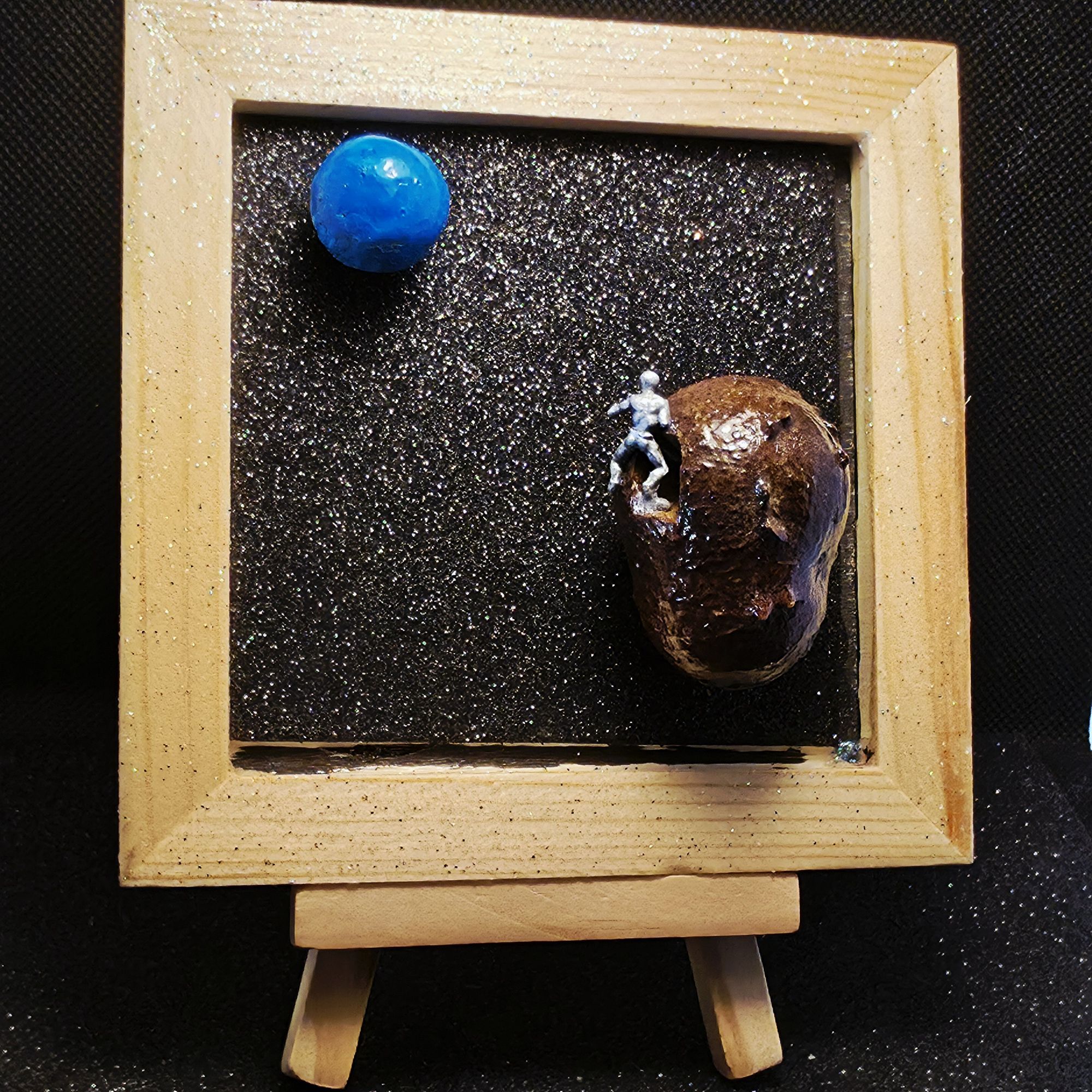 Petit tableau présentant un alien extraterrestre sortant d'un vaisseau spatial qui se dirige vers la terre, devenue la planète bleue à cause du réchauffement climatique