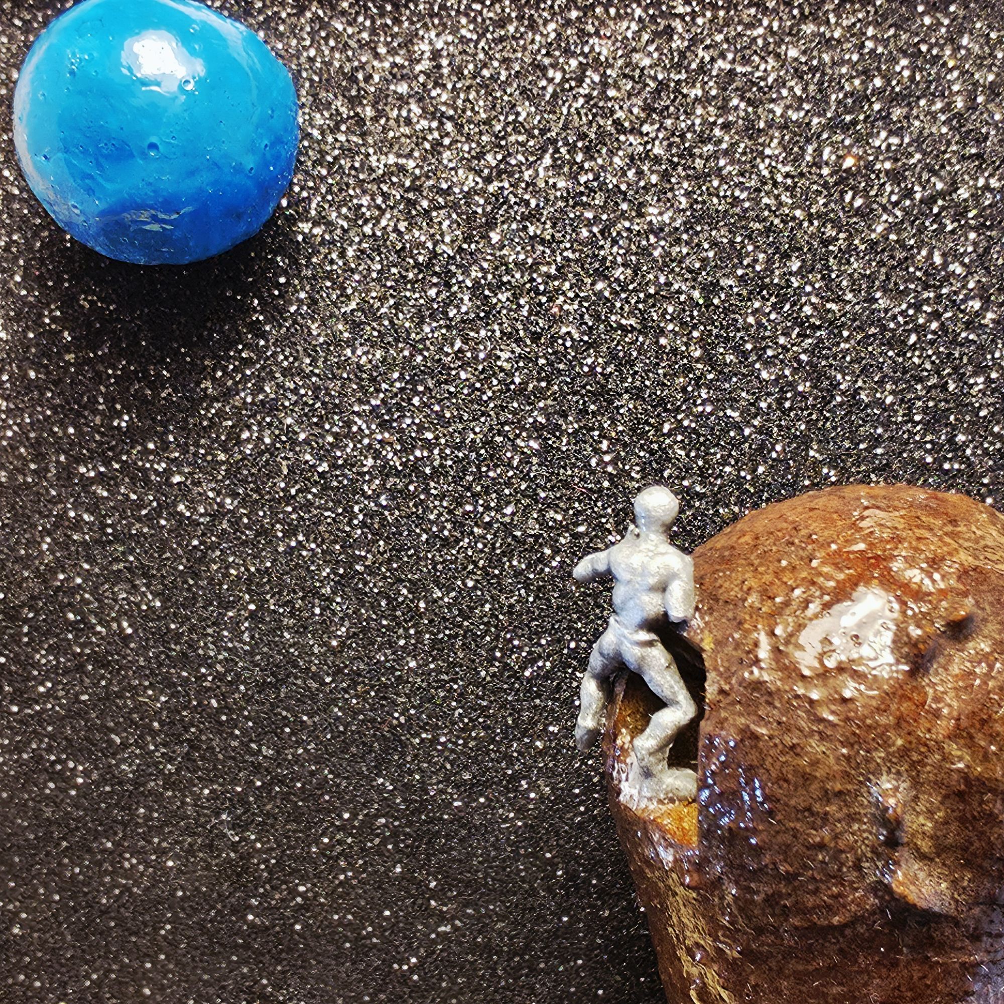 Petit tableau présentant un alien extraterrestre sortant d'un vaisseau spatial qui se dirige vers la terre, devenue la planète bleue à cause du réchauffement climatique